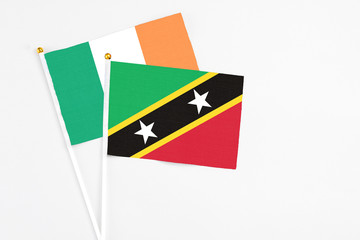 Saint Kitts And Nevis and Ireland stick flags on white background. High quality fabric, miniature national flag. Peaceful global concept.White floor for copy space