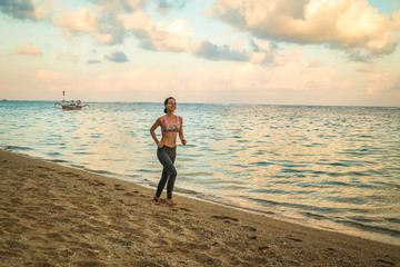 Woman jogging at the beach. Woman running barefoot during sunset. Healthy lifestyle. Indonesia, Bali, Pandawa beach.