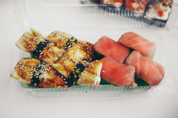 Japanese cuisine: rolls in a plastic container. Sushi on white background. Advertising concept of traditional Oriental cuisine, fish food: salmon, tuna, rice