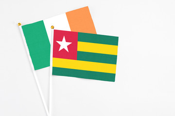 Togo and Ireland stick flags on white background. High quality fabric, miniature national flag. Peaceful global concept.White floor for copy space