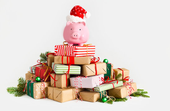 Piggy bank in santa claus hat. Christmas gift boxes. White background. The concept of saving.