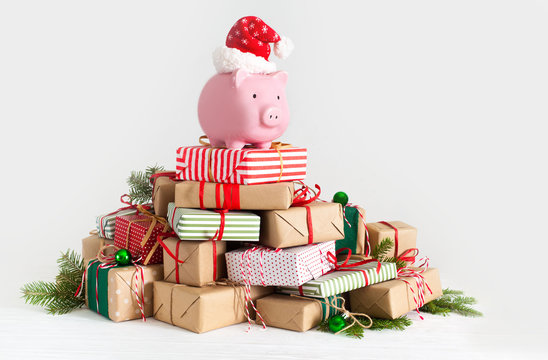 Piggy bank in santa claus hat. Christmas gift boxes. White background. The concept of saving.