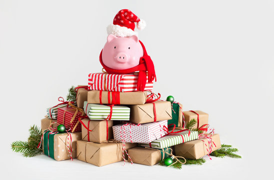Piggy bank in santa claus hat. Christmas gift boxes. White background. The concept of saving.