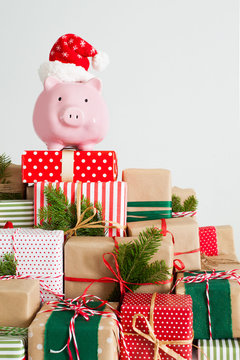 Piggy bank in santa claus hat. Christmas gift boxes. White background. The concept of saving.