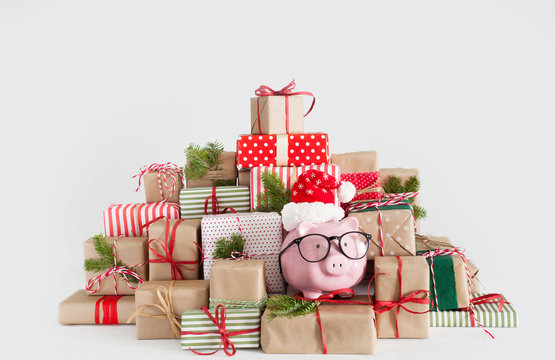 Piggy bank in santa claus hat. Christmas gift boxes. White background. The concept of saving.