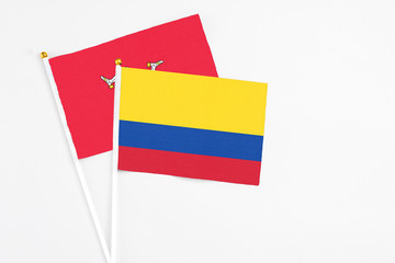 Colombia and Isle Of Man stick flags on white background. High quality fabric, miniature national flag. Peaceful global concept.White floor for copy space.