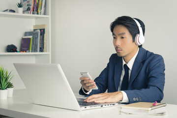 Asian Man Call Center Answer Customer Questions by Smartphone and Laptop in Vintage Tone