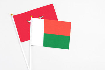Madagascar and Isle Of Man stick flags on white background. High quality fabric, miniature national flag. Peaceful global concept.White floor for copy space.