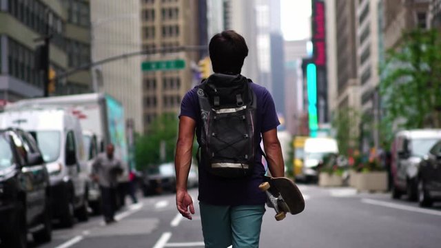 Hipster Guy With Skateboard Walking In New York City Street. Confident Millennial New Yorker. Concept Of Summer In NYC, Adventure, Healthy Living, Sport & Travel.