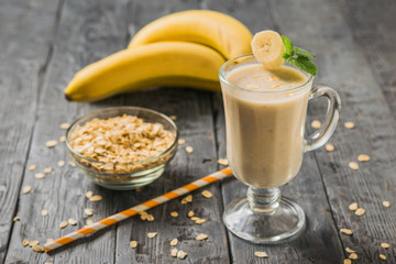 Banana smoothie and oatmeal scattered on a wooden table. Vegetarian smoothie.