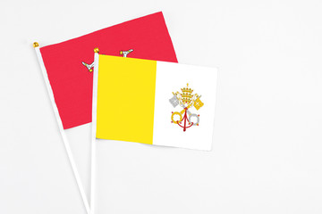 Vatican City and Isle Of Man stick flags on white background. High quality fabric, miniature national flag. Peaceful global concept.White floor for copy space.