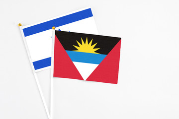 Antigua and Barbuda and Israel stick flags on white background. High quality fabric, miniature national flag. Peaceful global concept.White floor for copy space.