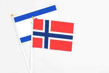 Obraz premium Bouvet Islands and Israel stick flags on white background. High quality fabric, miniature national flag. Peaceful global concept.White floor for copy space.