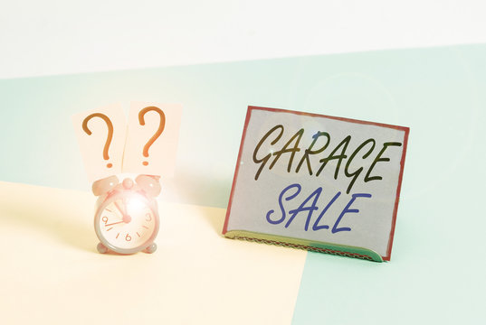 Word writing text Garage Sale. Business photo showcasing sale of miscellaneous household goods often held in the garage Mini size alarm clock beside a Paper sheet placed tilted on pastel backdrop