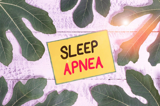 Handwriting text writing Sleep Apnea. Conceptual photo disorder which demonstrating repeatedly stop breathing when asleep Leaves surrounding notepaper above a classic wooden table as the background