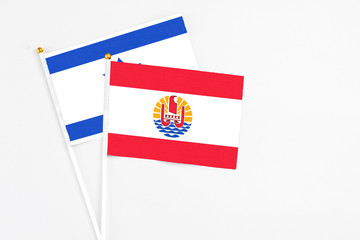 French Polynesia and Israel stick flags on white background. High quality fabric, miniature national flag. Peaceful global concept.White floor for copy space.