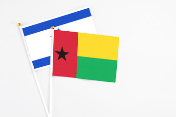 Guinea Bissau and Israel stick flags on white background. High quality fabric, miniature national flag. Peaceful global concept.White floor for copy space.