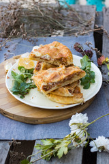 Lobiani - traditional baked Georgian pie with lobio beans and filo puff pastry. On plate with lemon slice, green rucola leaves and garlic. Homemade.