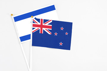 Fototapeta premium New Zealand and Israel stick flags on white background. High quality fabric, miniature national flag. Peaceful global concept.White floor for copy space.