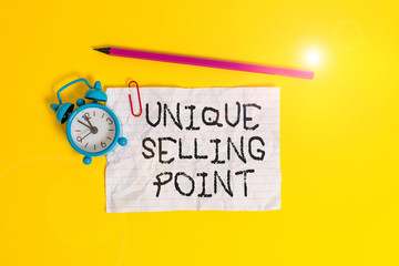 Conceptual hand writing showing Unique Selling Point. Concept meaning Differentiate a Product Specific Features and Benefits Metal alarm clock ccrushed sheet pencil colored background