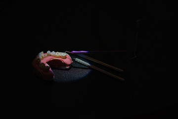 Teeth, denture, artificial jaw and dentist tools on a black background.