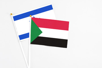 Sudan and Israel stick flags on white background. High quality fabric, miniature national flag. Peaceful global concept.White floor for copy space.