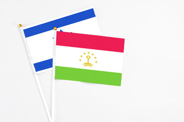 Tajikistan and Israel stick flags on white background. High quality fabric, miniature national flag. Peaceful global concept.White floor for copy space.