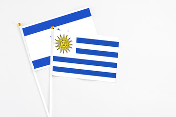 Obraz premium Uruguay and Israel stick flags on white background. High quality fabric, miniature national flag. Peaceful global concept.White floor for copy space.