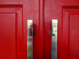 Silver door handle in red wood painted door