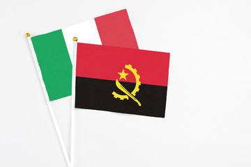 Angola and Italy stick flags on white background. High quality fabric, miniature national flag. Peaceful global concept.White floor for copy space.