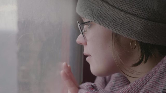 Close up of young attractive girl looking thoughtfully through window