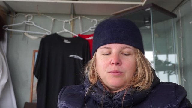 Woman in warm winter clothes tastes traditional Inuit Muktuk whale blubber in Arctic Tuktoyuktuk