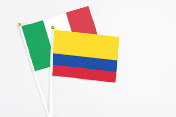 Colombia and Italy stick flags on white background. High quality fabric, miniature national flag. Peaceful global concept.White floor for copy space.