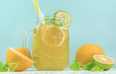 Lemonade drink of soda water, citrus and mint on the light blue background. Cocktail glass with...
