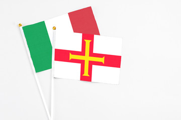 Guernsey and Italy stick flags on white background. High quality fabric, miniature national flag. Peaceful global concept.White floor for copy space.