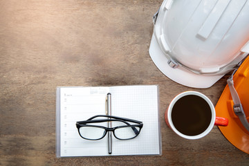 Fototapeta na wymiar Safety Engineer Helmet,notebook,glasses, pen and coffee cup on wood background.