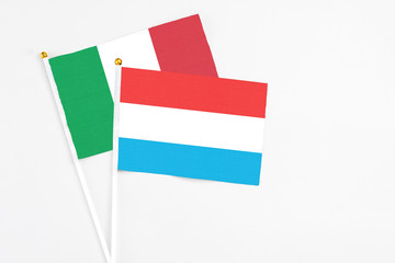 Luxembourg and Italy stick flags on white background. High quality fabric, miniature national flag. Peaceful global concept.White floor for copy space.