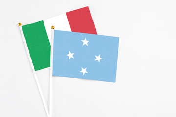 Micronesia and Italy stick flags on white background. High quality fabric, miniature national flag. Peaceful global concept.White floor for copy space.