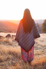 indigenous woman with a poncho in the sunset - 302823150