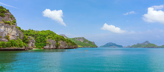 Fototapeta na wymiar Tourist kayaking in blue Idyllic turquoise ocean to explore near the island with lush green jungle trees and lime stone mountains at Ang Thong National Marine Park, Thailand.