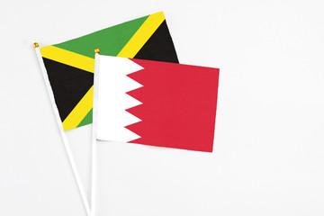 Bahrain and Jamaica stick flags on white background. High quality fabric, miniature national flag. Peaceful global concept.White floor for copy space.