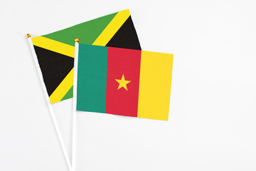 Cameroon and Jamaica stick flags on white background. High quality fabric, miniature national flag. Peaceful global concept.White floor for copy space.
