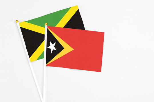 East Timor and Jamaica stick flags on white background. High quality fabric, miniature national flag. Peaceful global concept.White floor for copy space.