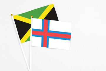 Faroe Islands and Jamaica stick flags on white background. High quality fabric, miniature national flag. Peaceful global concept.White floor for copy space.