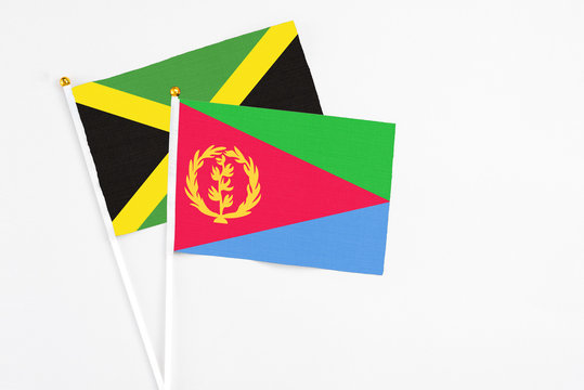 Eritrea and Jamaica stick flags on white background. High quality fabric, miniature national flag. Peaceful global concept.White floor for copy space.