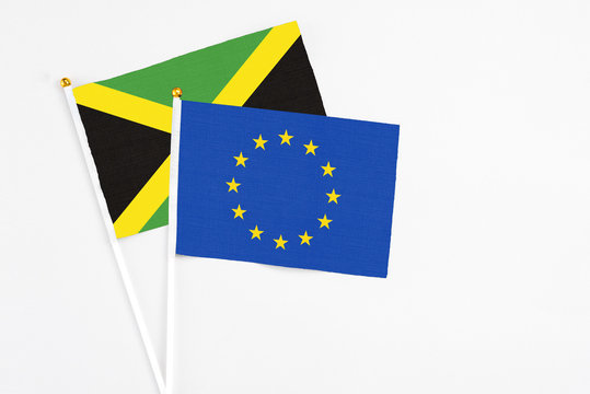 European Union and Jamaica stick flags on white background. High quality fabric, miniature national flag. Peaceful global concept.White floor for copy space.