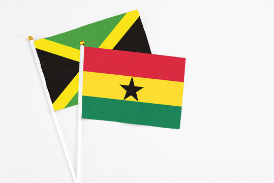 Ghana and Jamaica stick flags on white background. High quality fabric, miniature national flag. Peaceful global concept.White floor for copy space.