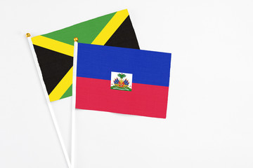 Haiti and Jamaica stick flags on white background. High quality fabric, miniature national flag. Peaceful global concept.White floor for copy space.