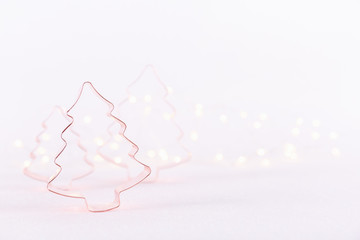 Assorted Christmas Tree Copper cookie cutters on white sparkling background with bokeh lights. Holiday Christmas and New Year background. Horizontal