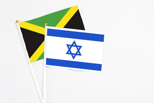 Israel and Jamaica stick flags on white background. High quality fabric, miniature national flag. Peaceful global concept.White floor for copy space.